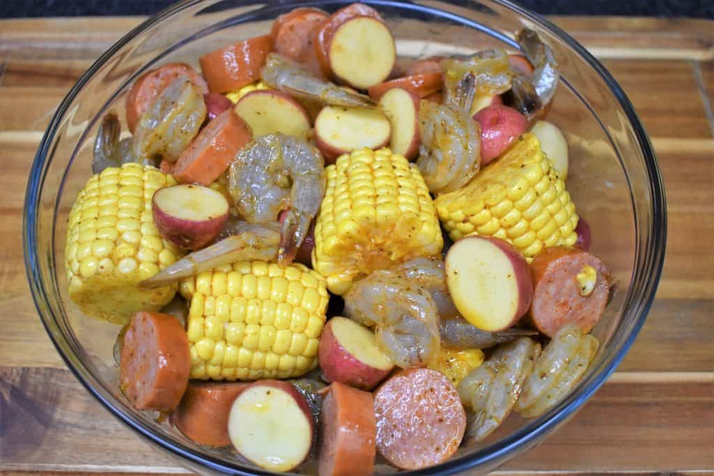 The ingredients for the sausage and shrimp foil packs in a large bowl.