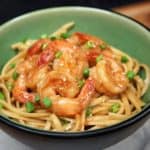 Shrimp & Sesame Noodles in a green bowl and garnished with sesame seeds and chopped green onions