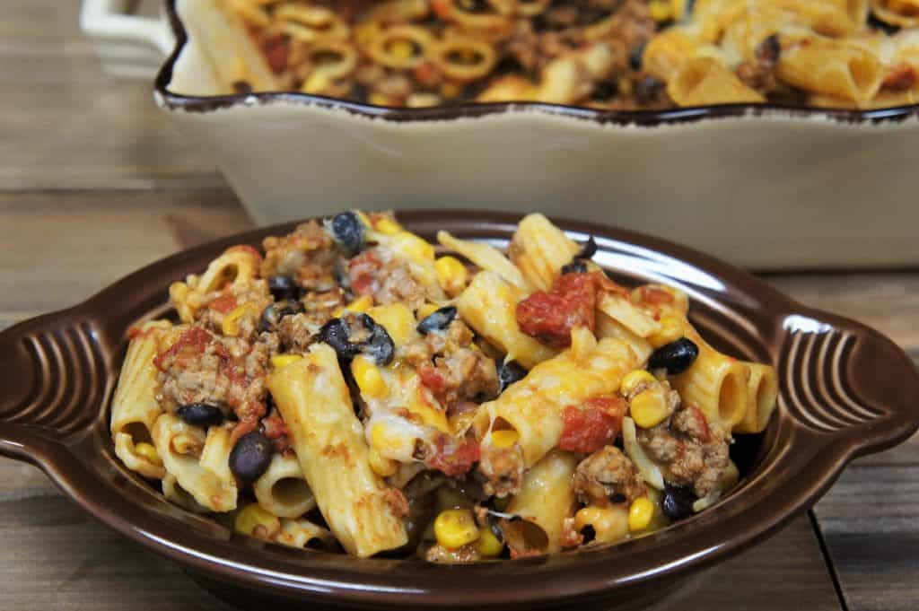 Southwestern Pasta in a brown bowl topped with melted cheese, black beans and corn