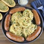 Spaghetti Aglio e Olio & Italian Sausage served on a gray platter with garlic toast in the background