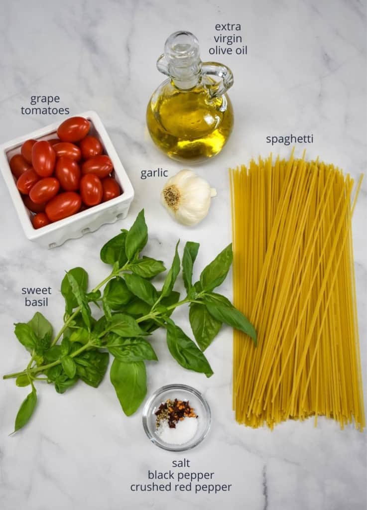 The ingredients for the dish arranged on a white table with each labeled with small black letters.