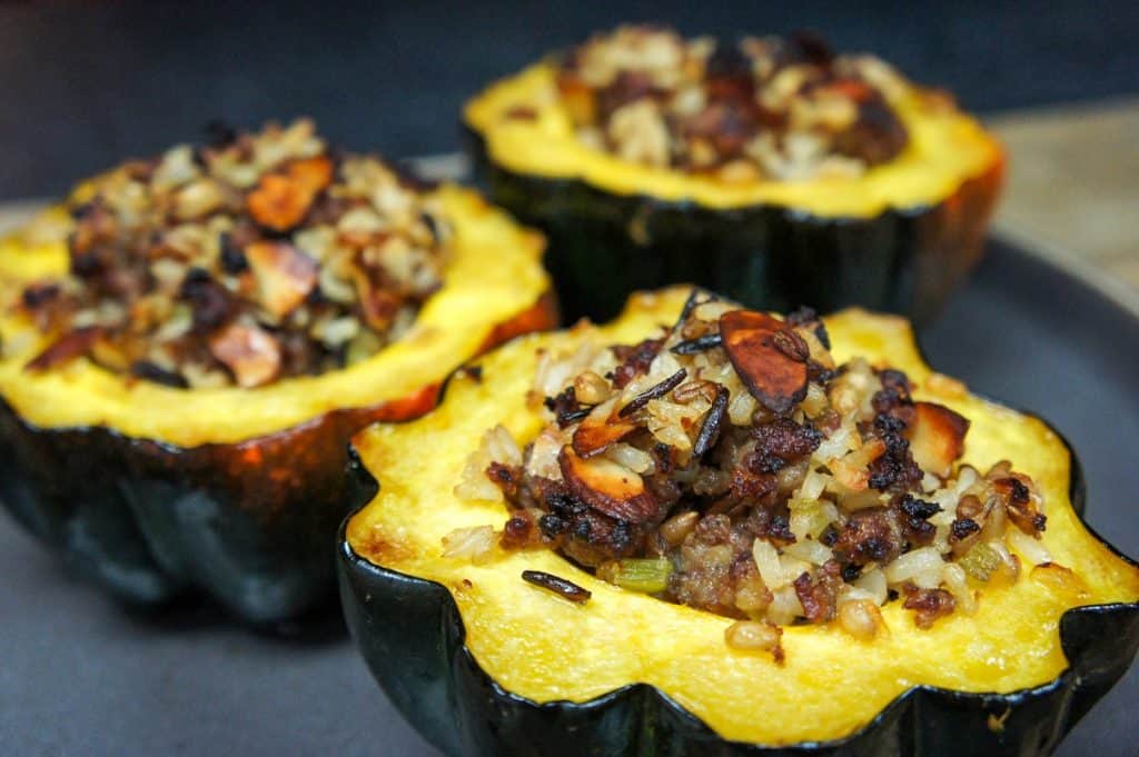 Three stuffed acorn squash arranged on a gray plate.