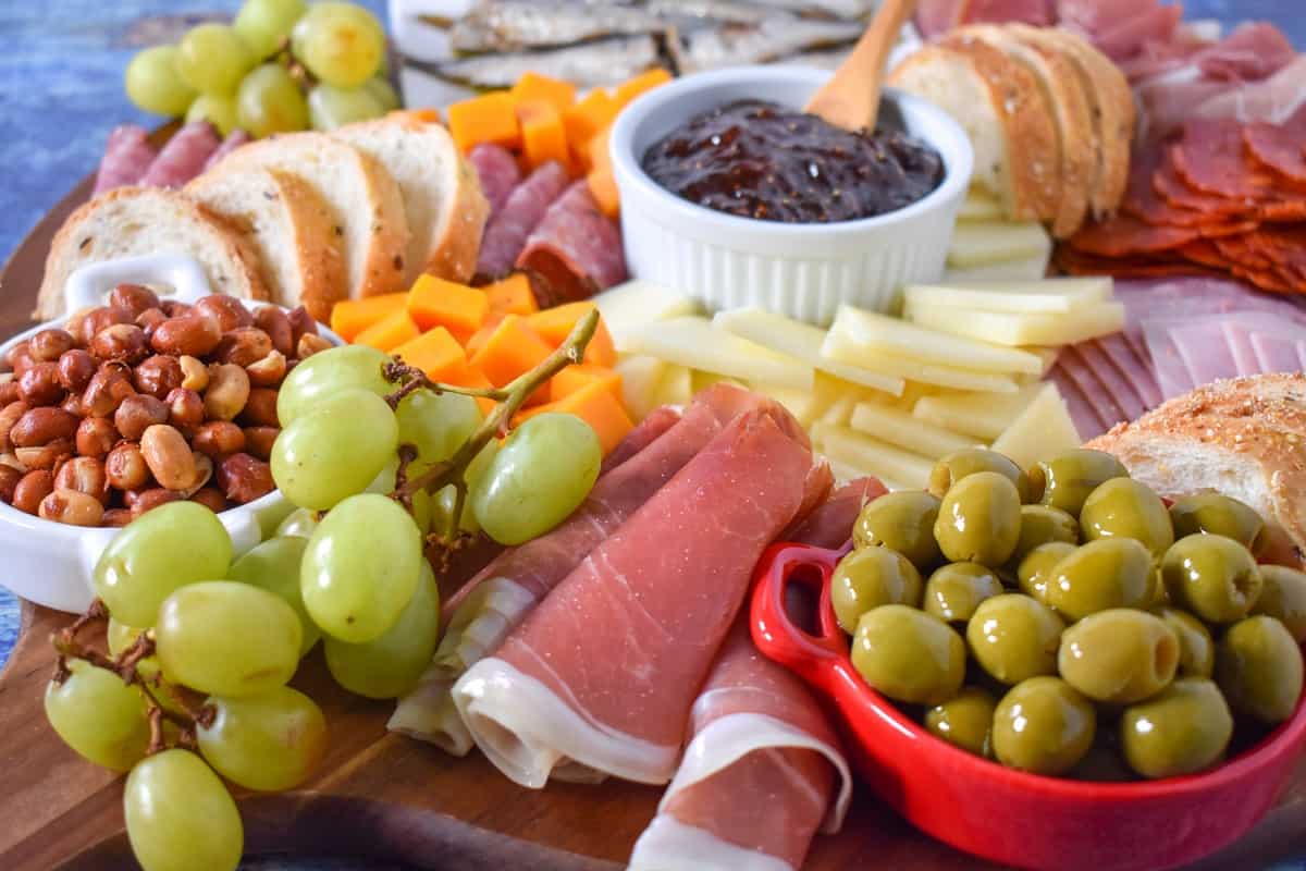 A close up of the tapas platter with serrano ham, grapes and olives in the forefront.