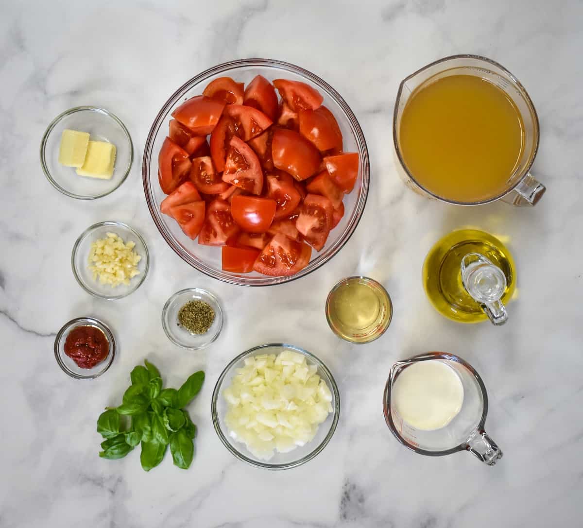 The ingredients for the soup, prepped and separated into glass containers all displayed on a white table.