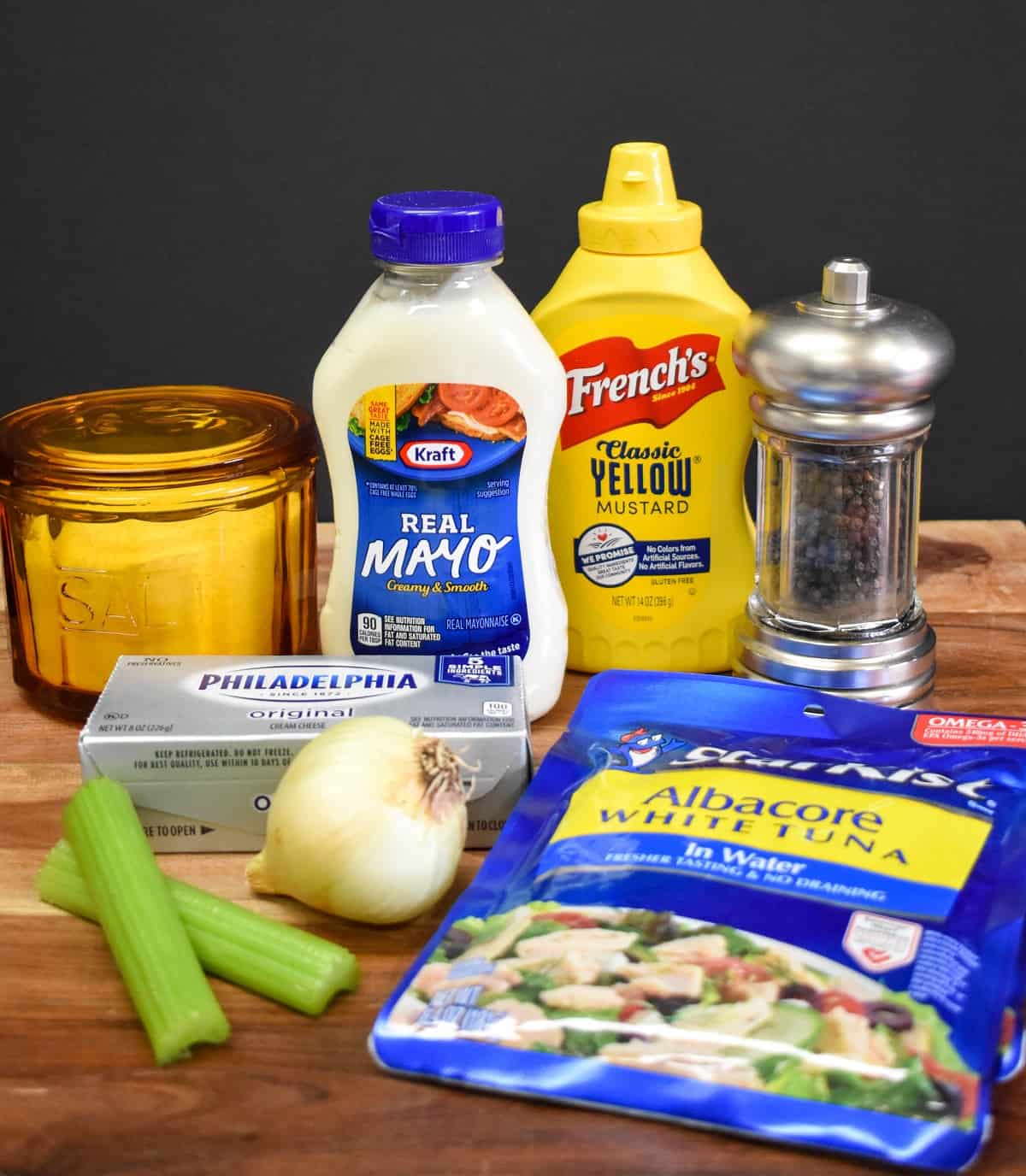 The ingredients for the tuna salad displayed on a wood cutting board.