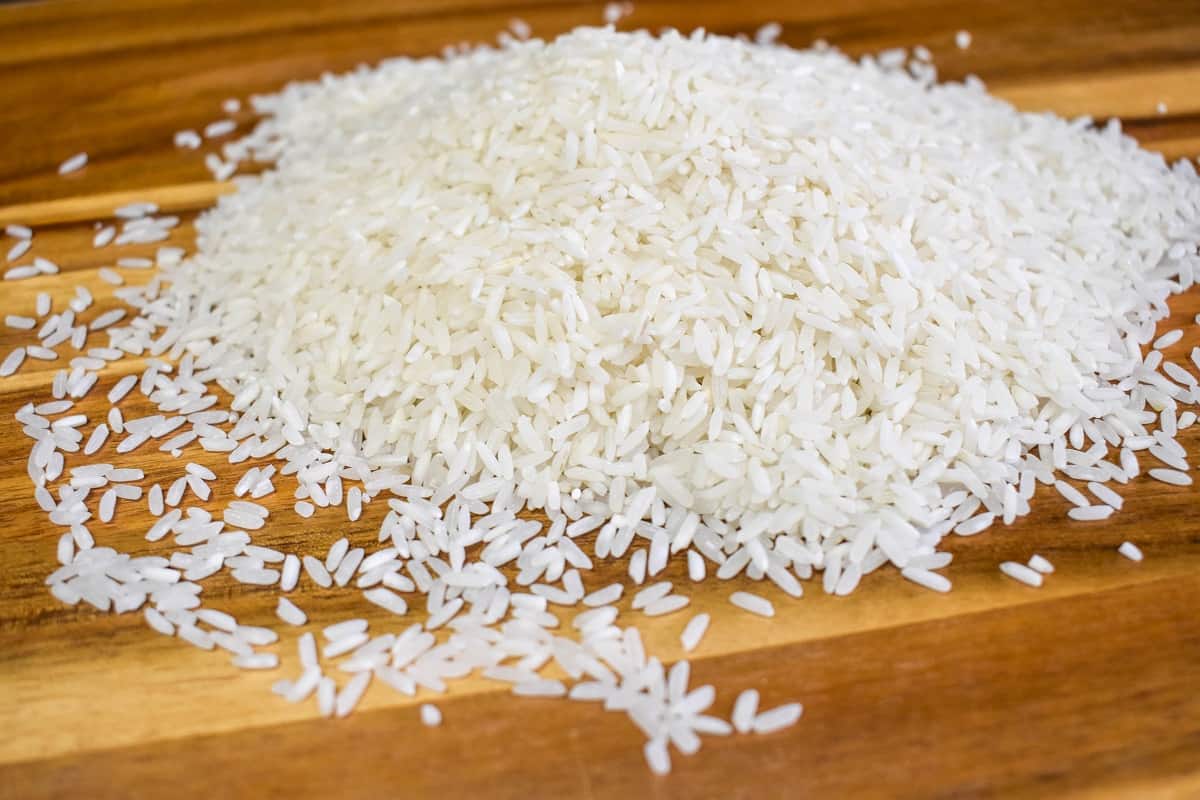 About one cup of uncooked rice in a small mound on a wood cutting board.