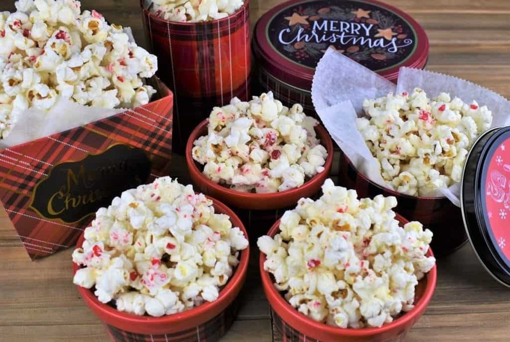 White Chocolate Peppermint Popcorn served in Christmas themed tins and bowls