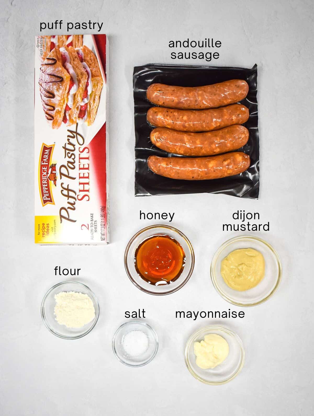 The ingredients for the sausage puffs and dipping sauce arranged on a white table.