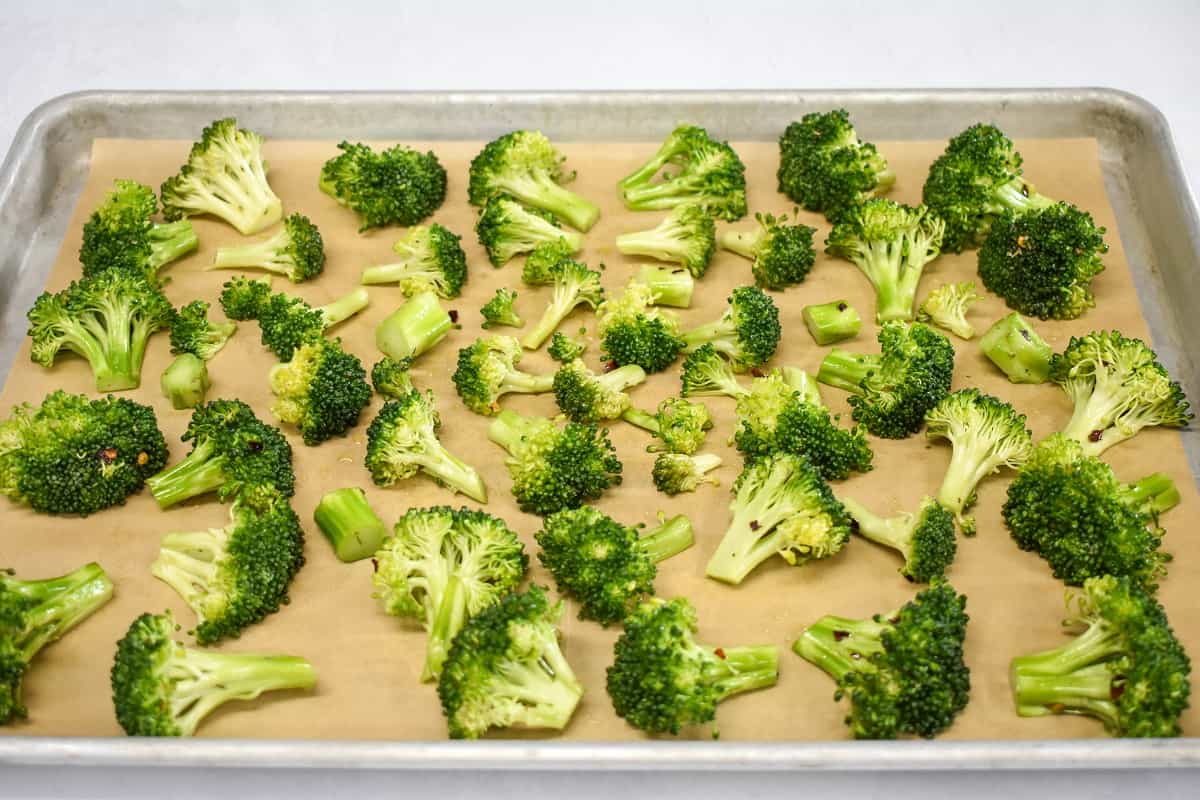 The coated broccoli florets arranged on a baking sheet lined with parchment paper.