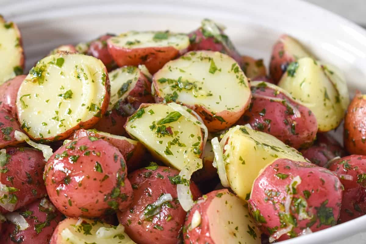 A close up of the chimichurri potatoes in a white bowl.