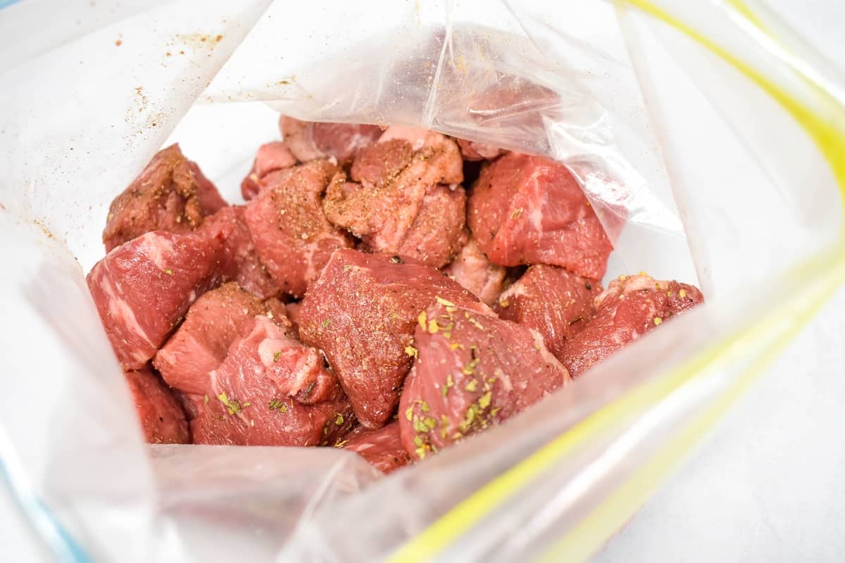 Seasoned beef chunks in a zip top bag.