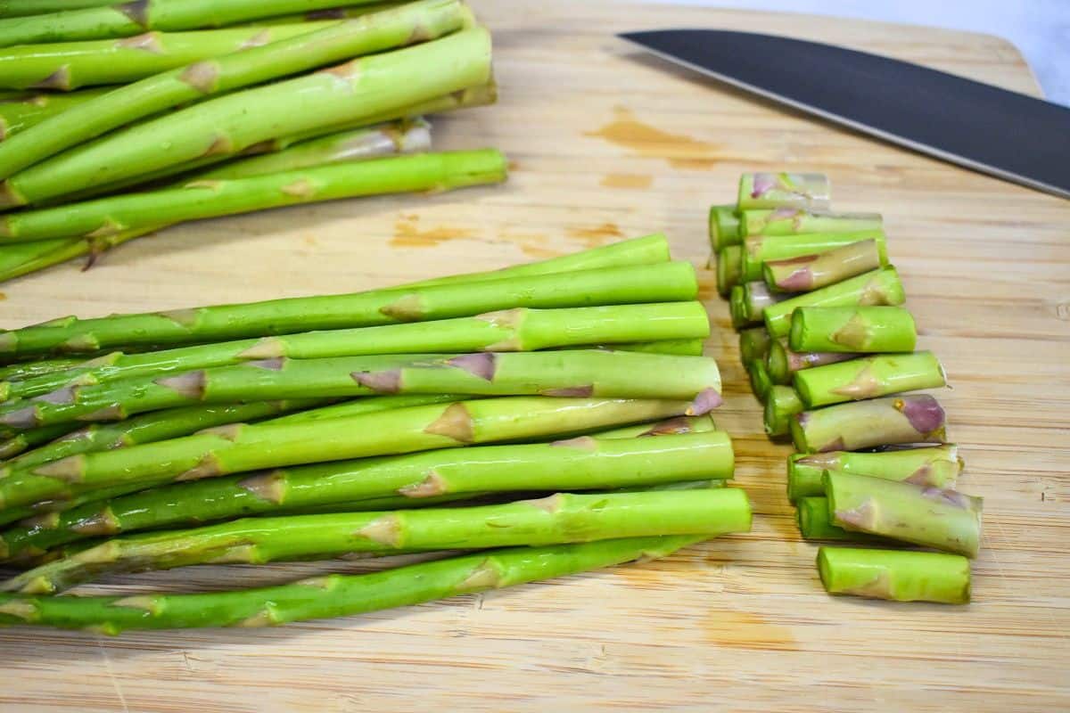 Fresh asparagus spears with the woody ends trimmed off on a cutting board.