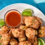 Fried pork chunks on a white plate with a small bowl of hot sauce and lime wedges. There is a teal graphic above with the title in white letters.