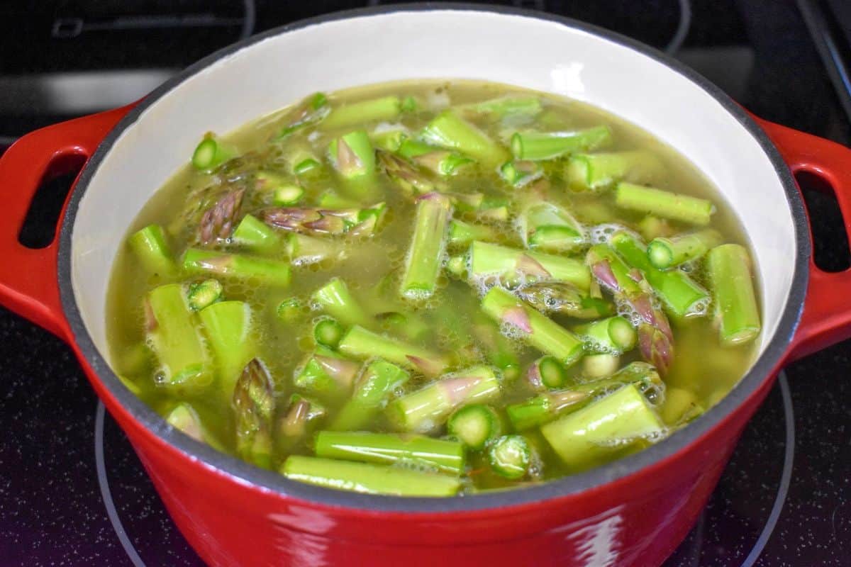 Asparagus and vegetables simmering in chicken broth before the soup is puréed.