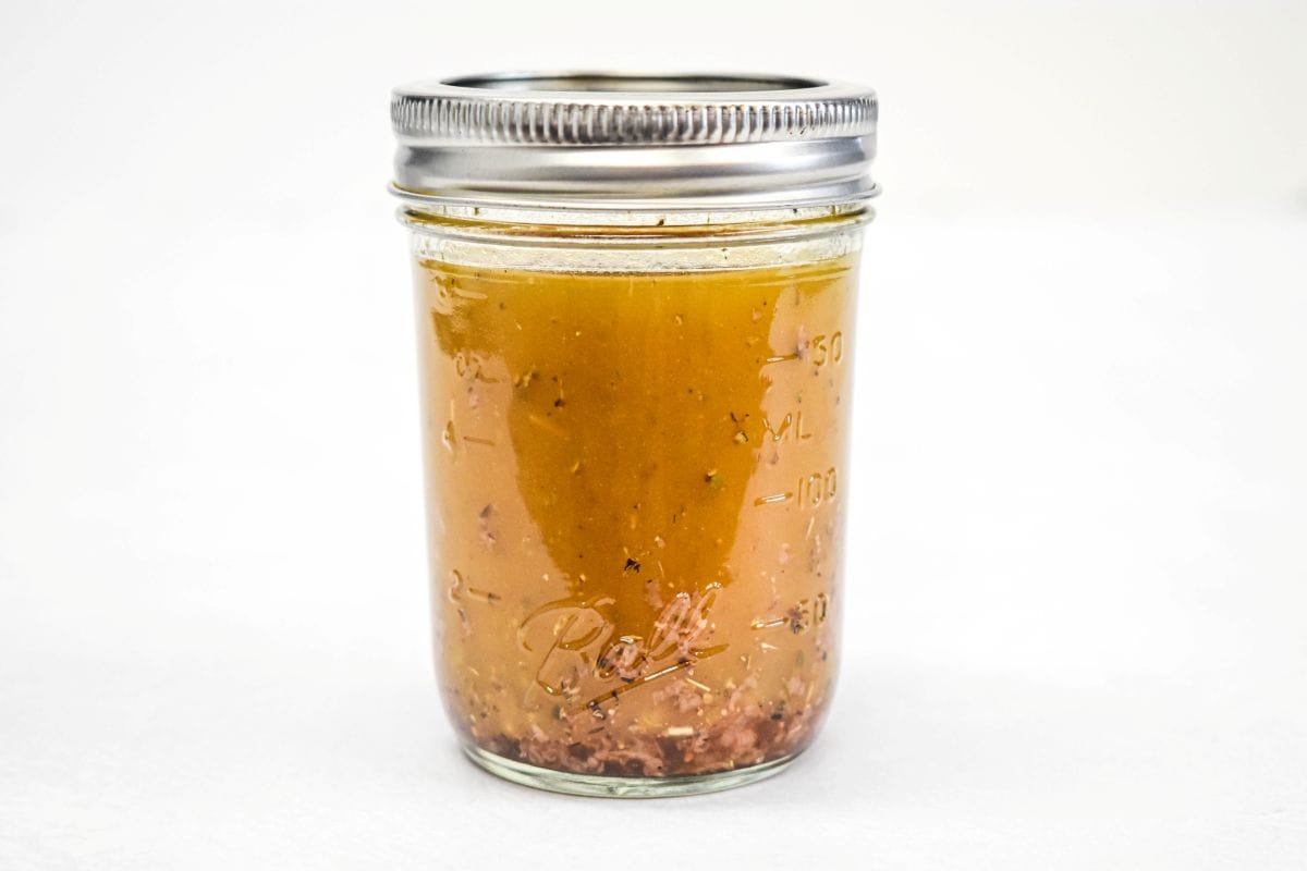 Mixed oil and vinegar dressing for garden pasta salad in a glass jar.