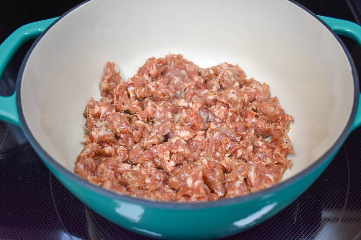 Crumbled Italian sausage cooking in a large pot.