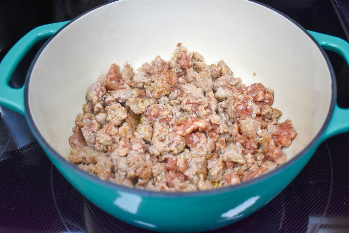 Crumbed Italian sausage browning in a large pot.