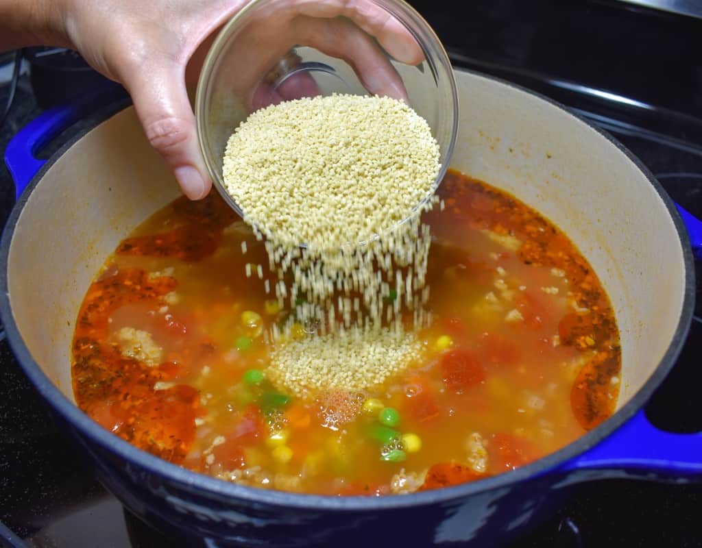 An image showing the pastina being added to the soup.
