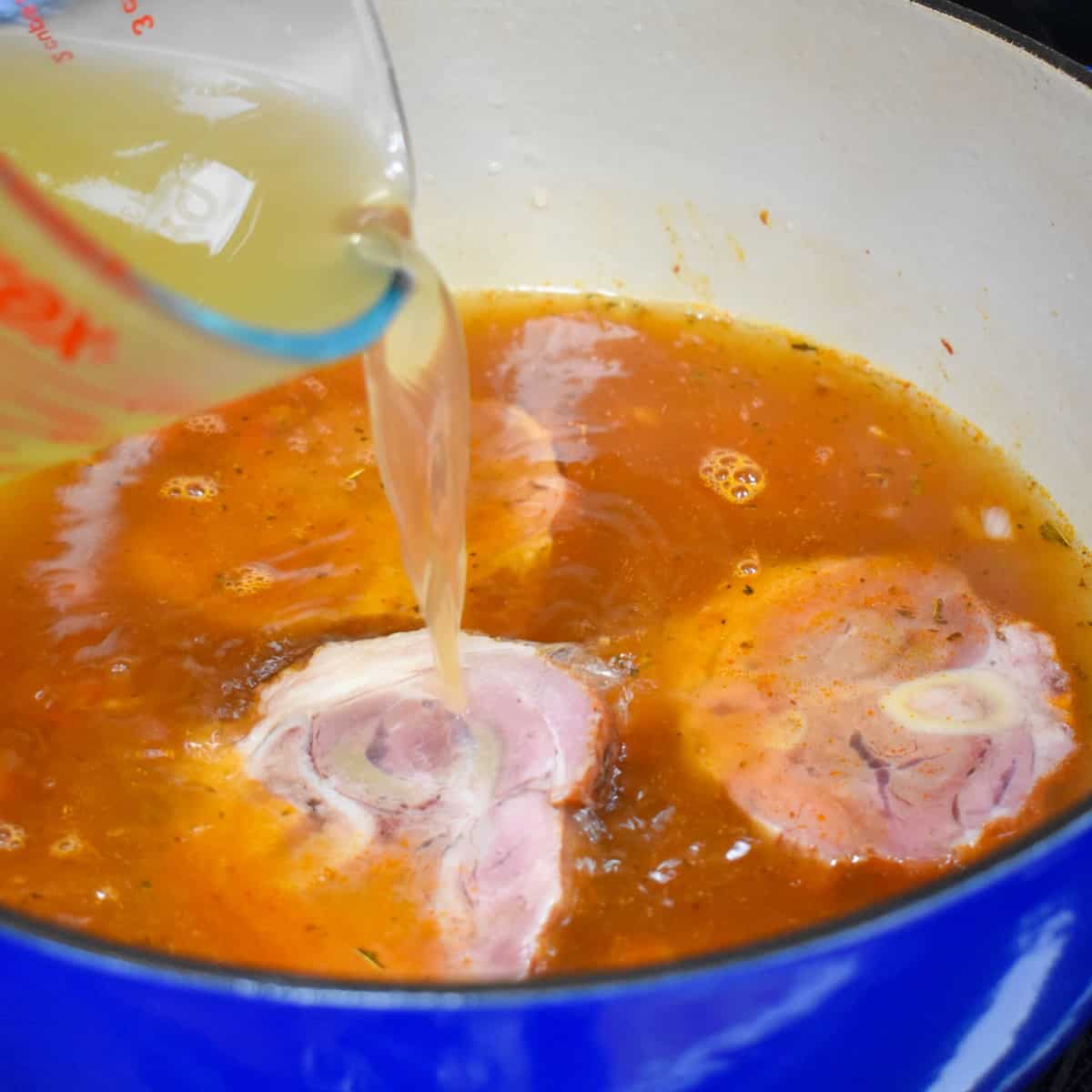Chicken broth being poured in to the pot.