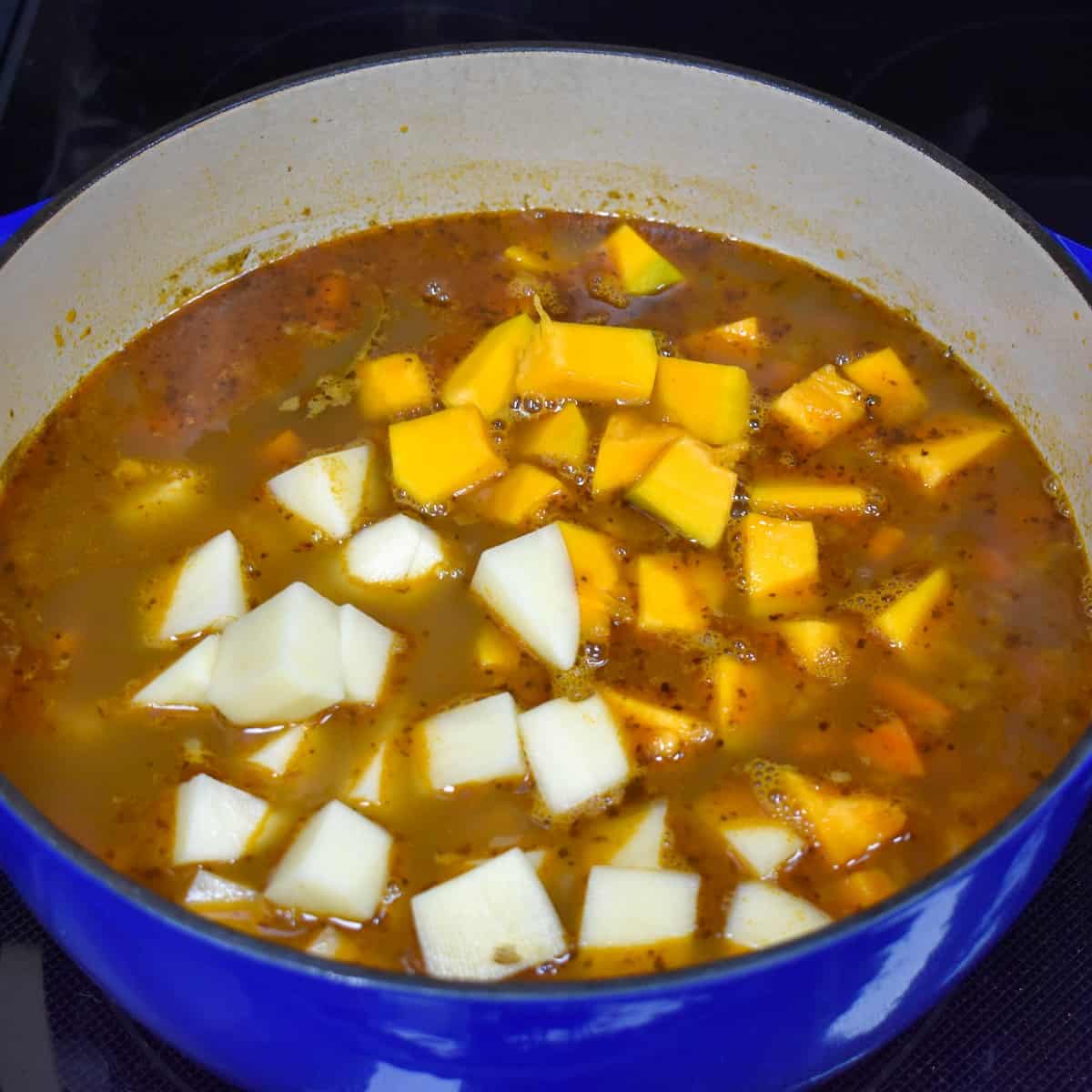 Cut potatoes and pumpkin pieces added to the broth for the soup.