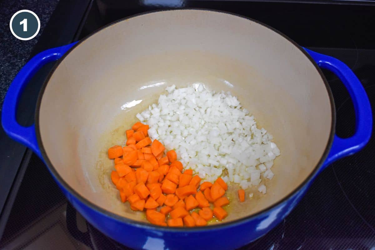 Onions and carrots cooking in olive oil in a Dutch oven.