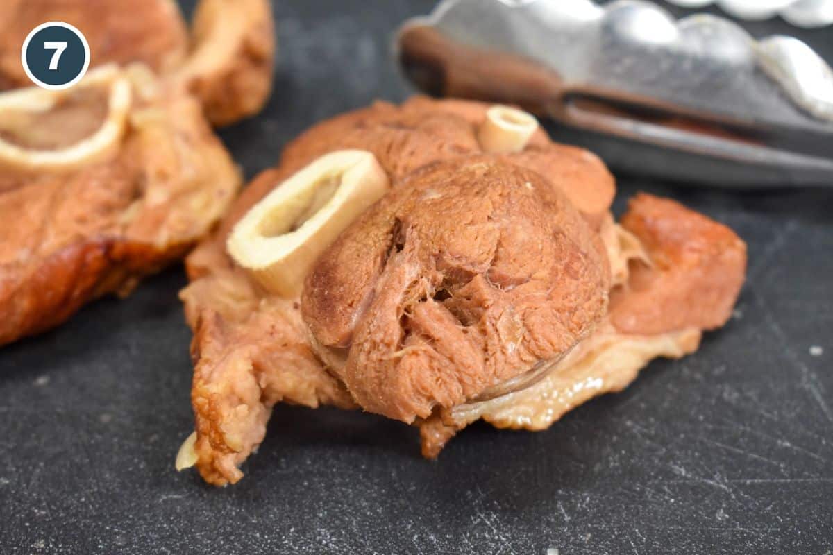 Cooked ham shanks on a cutting board.