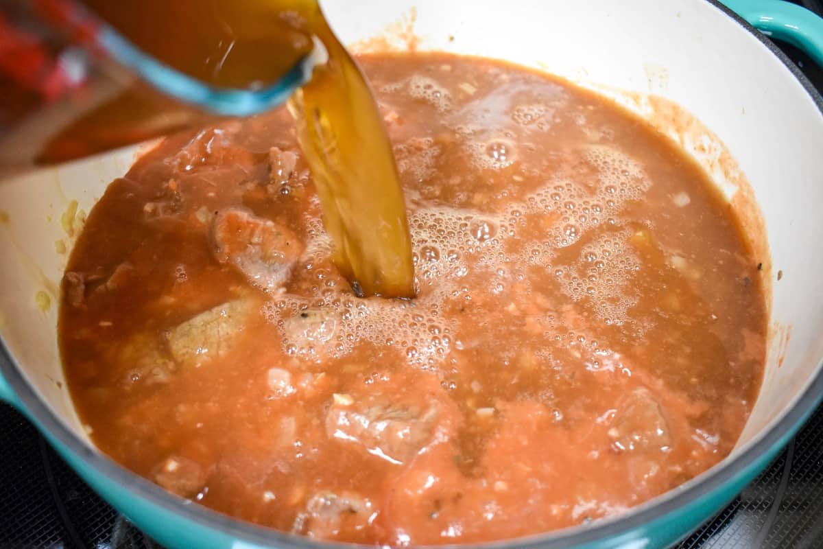 Beef broth being added to the soup in the pot.