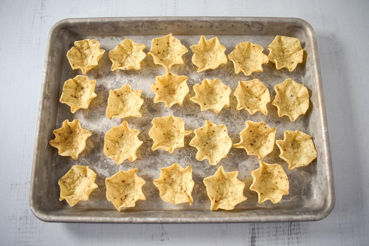 An image of tortilla scoop chips arranged on a baking sheet.