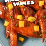 Mango habanero wings arranged on a blue platter and garnished with diced mango and parsley.