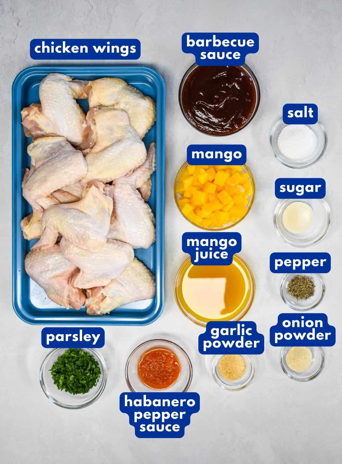 The ingredients for the habanero wings prepped and arranged on a white table with each labeled in blue and white letters.