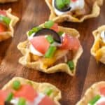 A close-up of the mini taco bites on a wood cutting board.