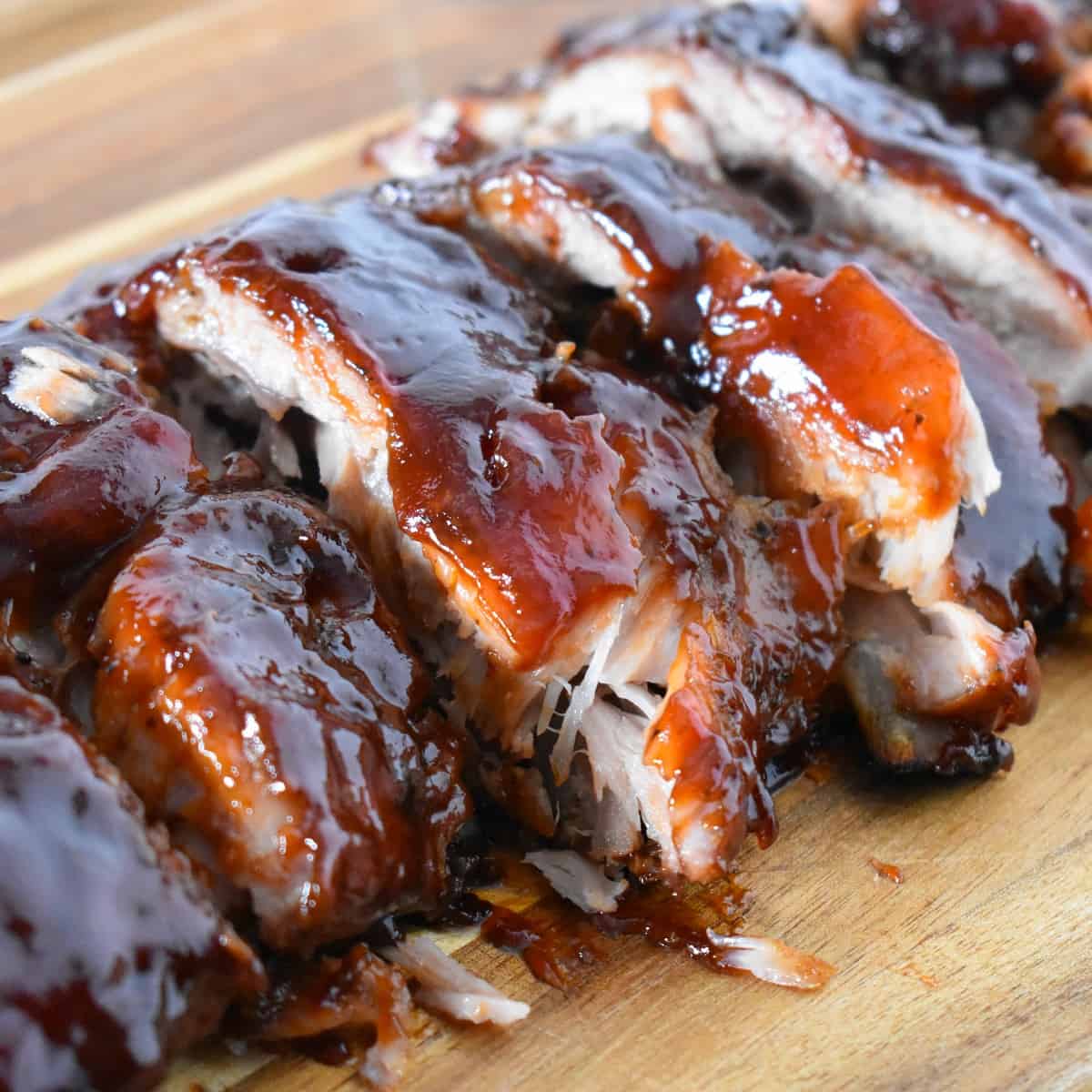 The finished oven barbecue ribs cut on a wood cutting board.