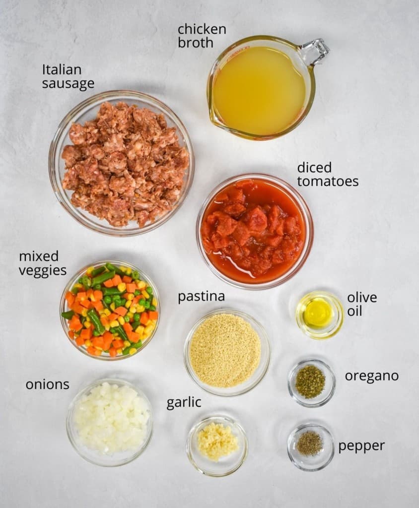 The ingredients for the soup, prepped and arranged in glass bowls on a white table. Each ingredient has a label in small black letters.