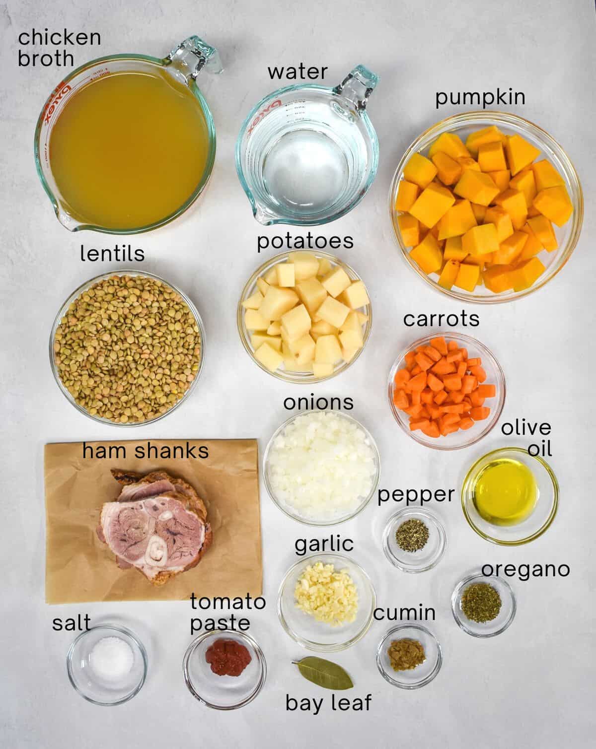 The ingredients for the soup arranged on a white table, each has small text with the name.