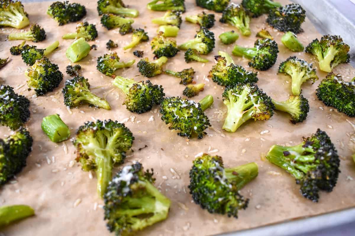 The roasted broccoli still on the parchment lined baking sheet.
