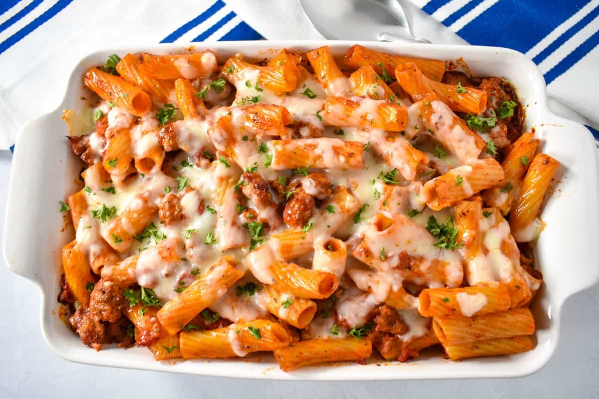 The baked sausage rigatoni in a white baking dish, garnished with parsley.