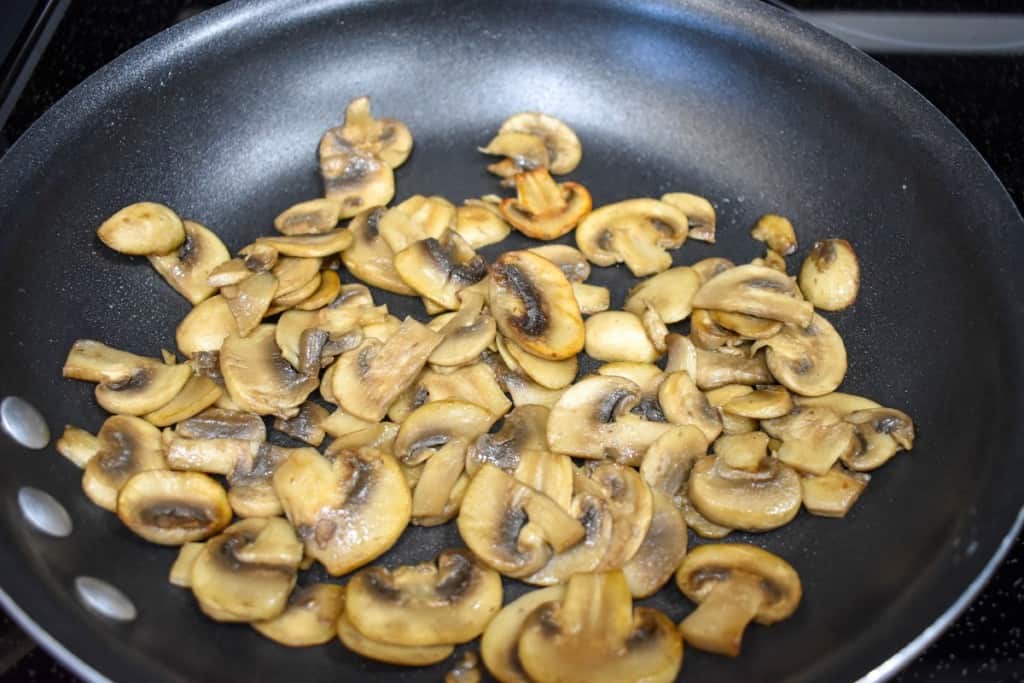 Sautéed mushrooms in a non-stick black skillet.