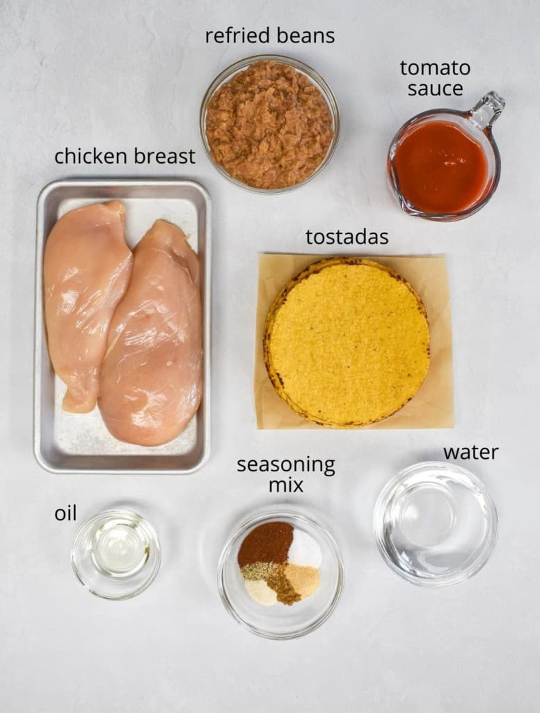 The ingredients, except the toppings, arranged on a white table. Each ingredient has a label above in small, black letters.