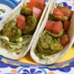 Cilantro Lime Shrimp Tacos served in flour tortillas, the shrimp are coated in a cilantro sauce and topped with diced tomatoes