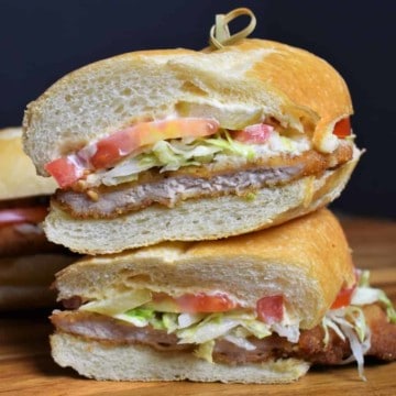 Fried Pork Sandwich, served on a sub roll with shredded lettuce, tomatoes and mayo, cut in half and stacked.