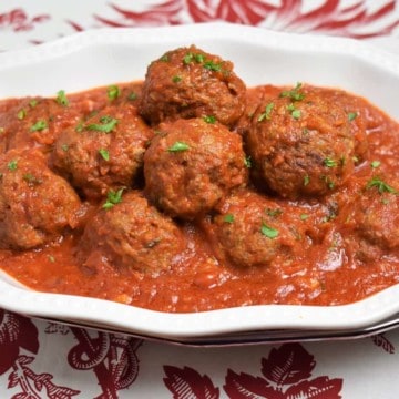 Meatballs Cuban Style served on a white platter in a red sauce and garnished with chopped parsley