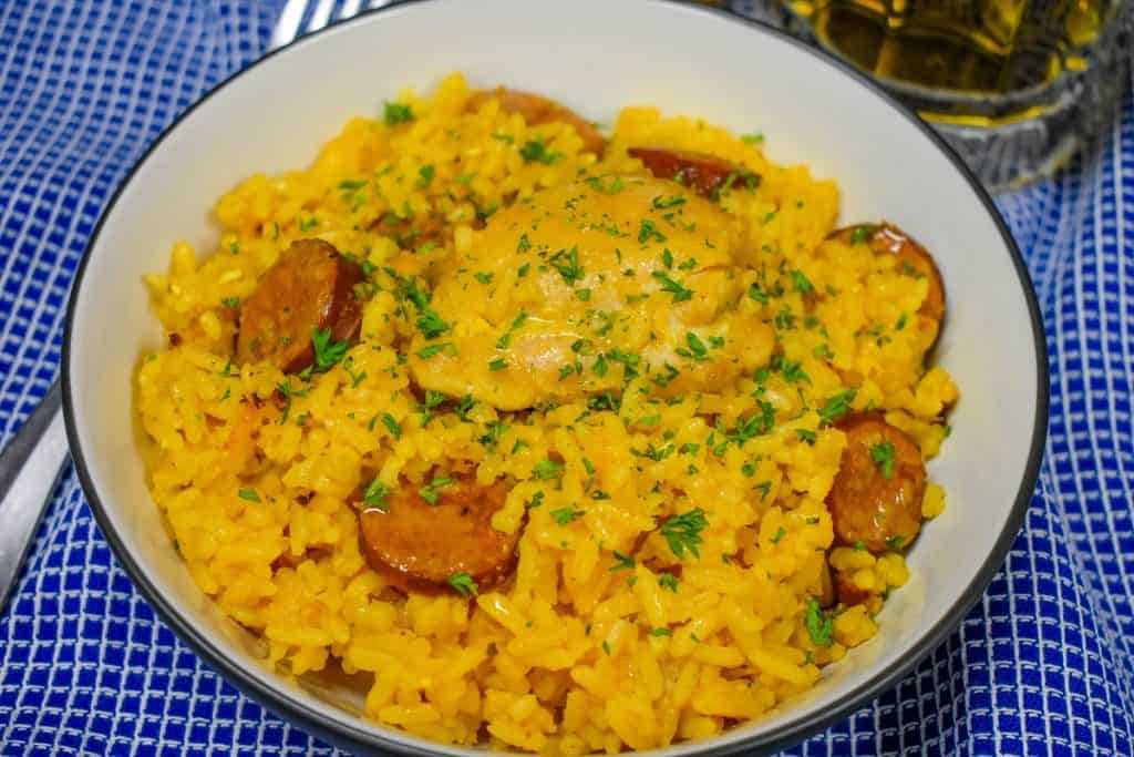 Yellow Spanish Rice with chicken and sausage served in a white bowl