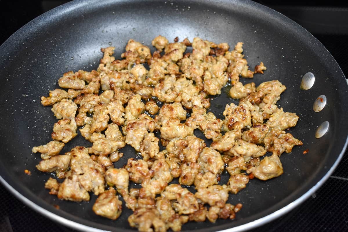 An image of cooked sausage in a non-stick skillet.