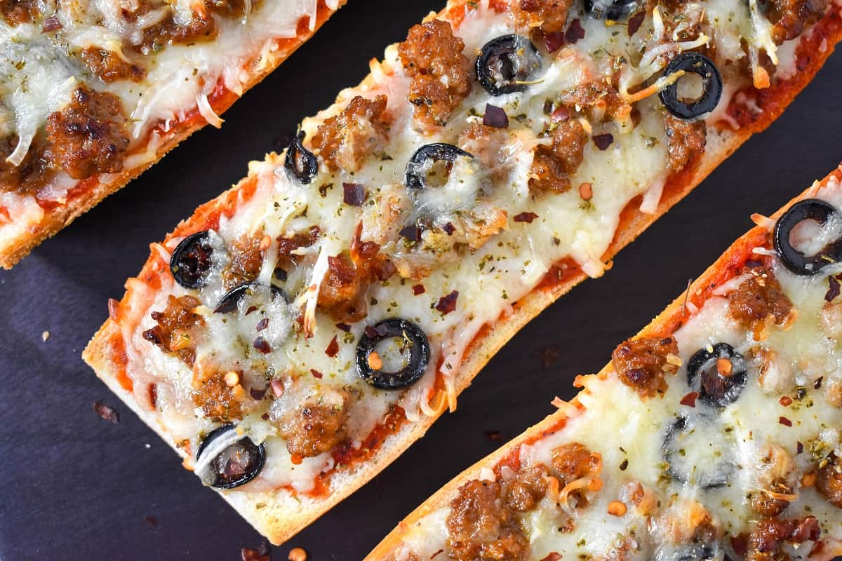 A close-up image of the finished French bread pizza on a black cutting board.