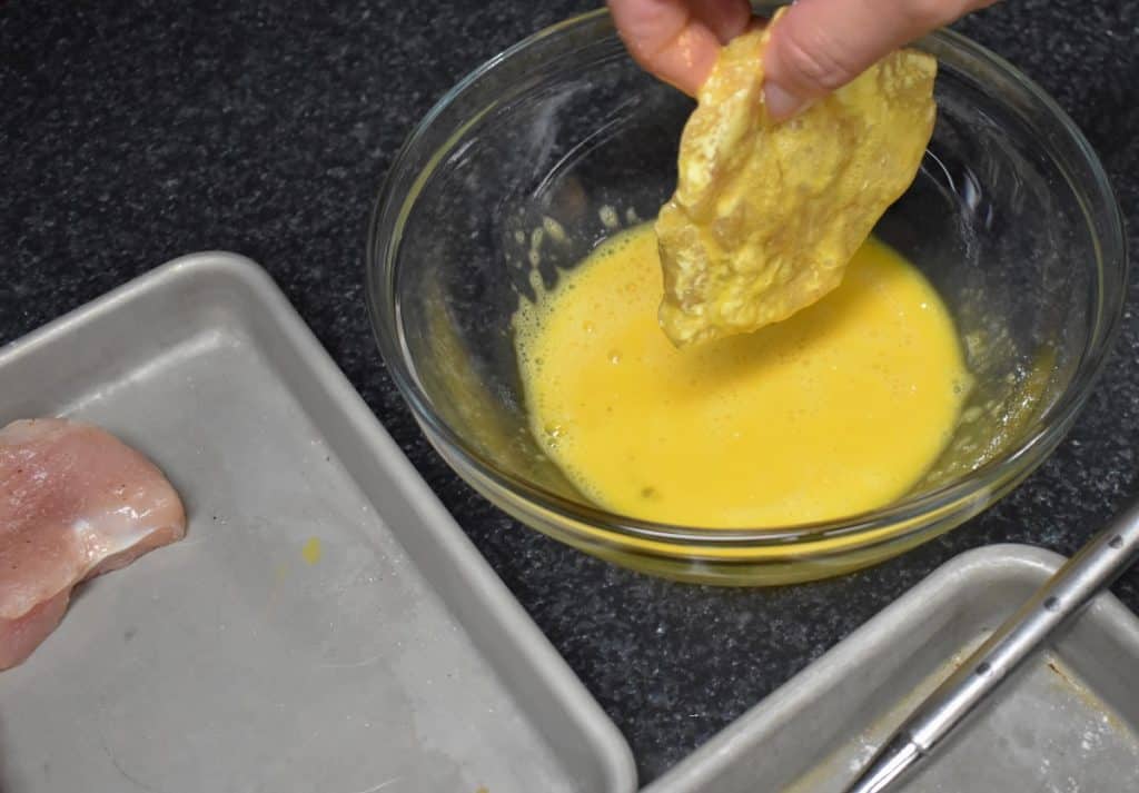 Egg Dip, a chicken breast cutlet that was previously dredged in flour is dipped in egg and held over the bowl