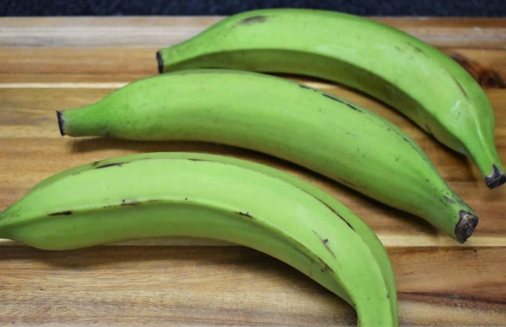 Green Plantains for tostones, uncut and arranged on a cutting board