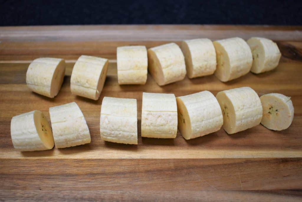 Green plantains for tostones sliced into roughly one each pieces and arranged on a cutting board