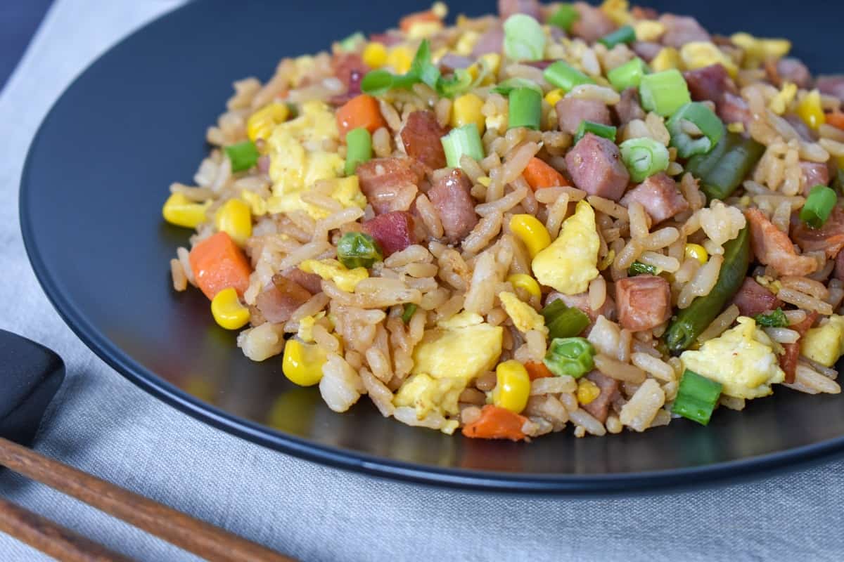 The finished fried rice served on a black plate on a beige linen.