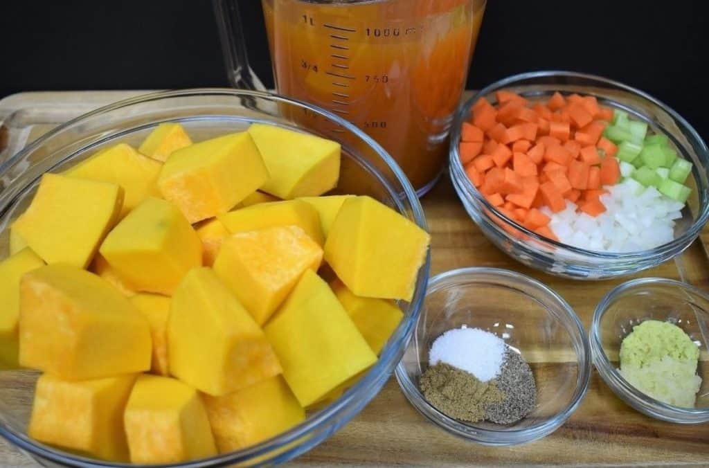 Pumpkin Soup Mise en Place three bowls with the raw ingredients for the soup and 4 cups of vegetable broth in a measuring cup