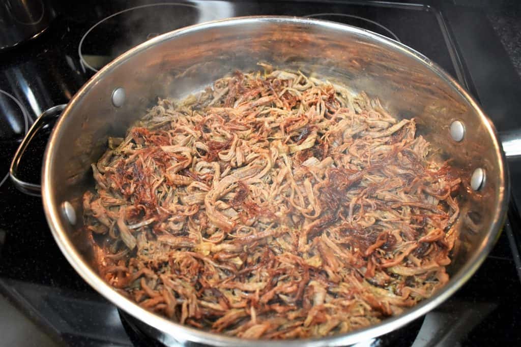 Shredded beef arranged in a skillet with the crispy side up